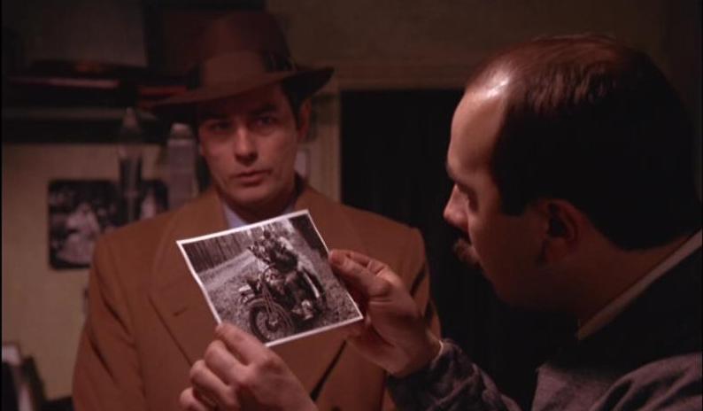 Figure 19: Here Klein, looking rather like a noir-style detective in trench coat and fedora and like the man pictured in the photograph, watches on as a photographer examines the redeveloped print.